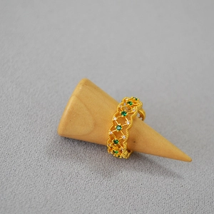 Detail of vintage gold ring with hollow lace pattern and emerald green zircon stones