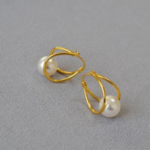 Detail shot of French style gold-plated double hoop earrings with a lustrous white pearl