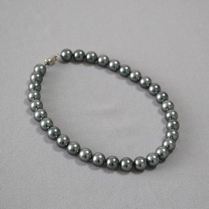 Close-up of high-luster dark grey pearl necklace with metallic silver lobster clasp detail