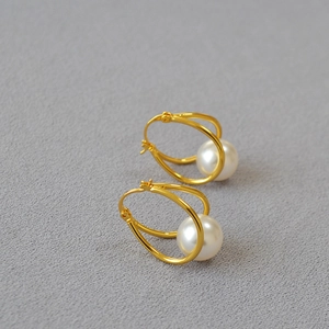 Detailed view of gold plated double loop earrings with elegant round white pearls