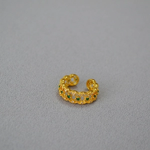 Detail of vintage hollow lace gold-plated ring with green zircon and white crystals