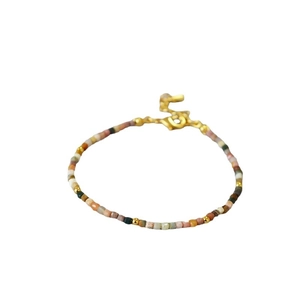 Minimalist bohemian beaded bracelet with earthy color tones and golden spacers on white back