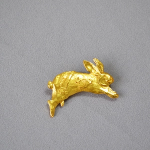 Close-up of golden rabbit brooch featuring engraved star and moon patterns on matte finish