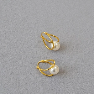 Macro detail of French gold-plated brass hoop earrings with elegant white pearls