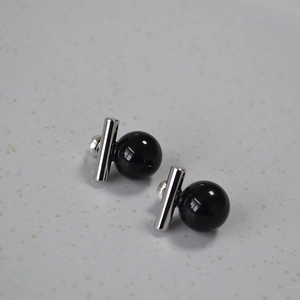 Vue macro de boucles d'oreilles minimalistes en perle noire avec barre d'argent et tiges 925