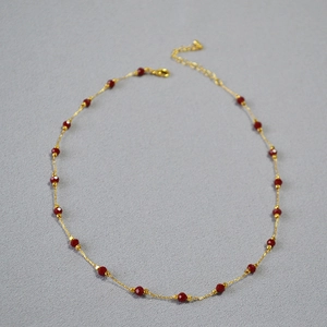 Close-up of minimalist gold-plated necklace with faceted red cinnabar spinel beads