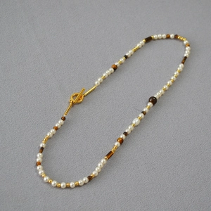 Detail of vintage beaded necklace with pearls, tiger eye stones and golden OT buckle