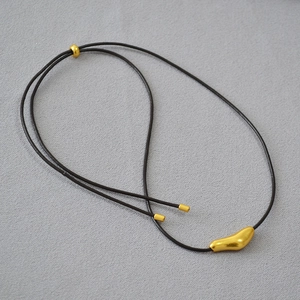 Detail of adjustable black cord necklace with minimalist gold irregular pendant