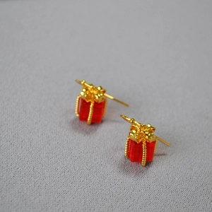 Detail view of red gift box earrings with golden ribbons and bows for holiday season