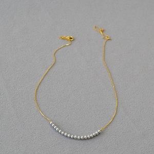 Minimalist gold necklace featuring blue grey beads and sleek lobster clasp closure