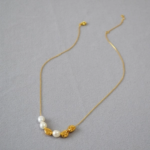 Detail of baroque freshwater pearl and gold bead necklace with lobster clasp and chain