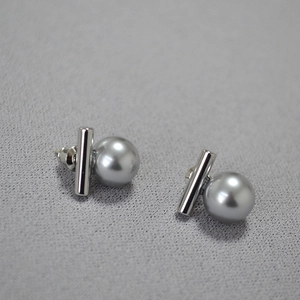 Détail de boucles d'oreilles en argent avec perles grises rondes sur tissu texturé