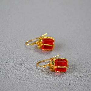 Festive red crystal gift box earrings with golden bows on a textured background