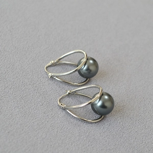 Macro detail of silver geometric dual-arc earrings with lustrous dark grey pearls
