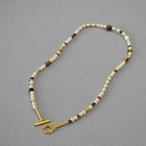 Macro detail of OT buckle necklace with white pearls and brown tiger eye stone beads