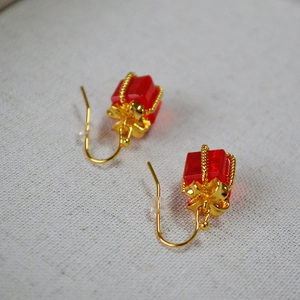 Close-up of red gift box earrings with golden bows and crystal ruby texture