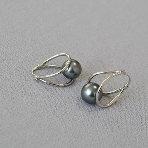 Detail of silver-plated double hoop earrings with a dark grey pearl centerpiece