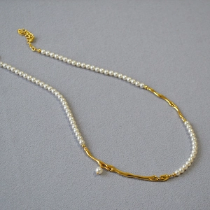 Vue détaillée du collier de perles avec des éléments de branche dorés texturés en lave