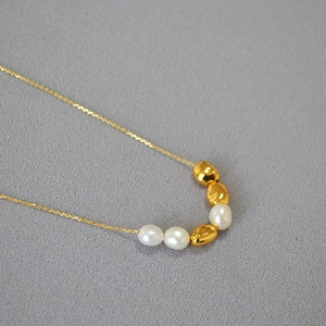 Baroque freshwater pearls and irregular gold bead short necklace on grey fabric background