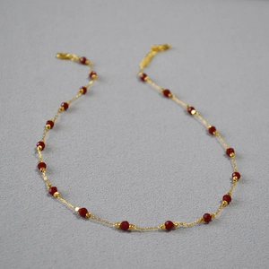 Detail of red faceted spinel beads on a gold-plated brass chain with extension link