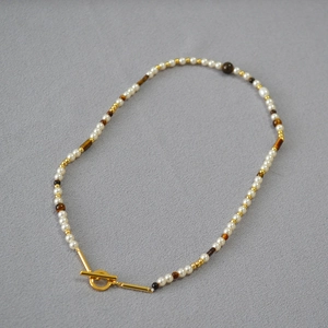 Detail of beaded necklace with tiger eye stones, pearls and a golden toggle clasp