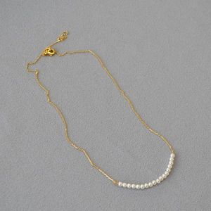 Detailed view of minimalist gold chain necklace with fifteen lustrous round white pearls