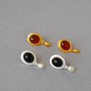 Detail of vintage teardrop earrings featuring black onyx and red oval gemstones set in metal