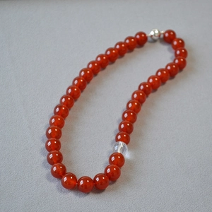 Detailed shot of red agate beaded necklace with clear crystal bead and silver clasp
