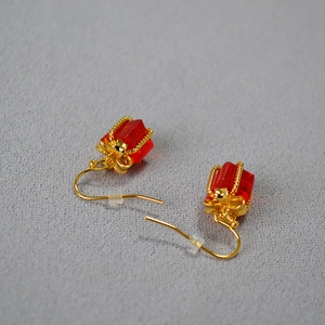 Macro detail of red crystal gift box earrings with golden wire wrap and ear hooks