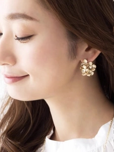 Macro detail of layered gold floral stud earrings featuring textured brass petals
