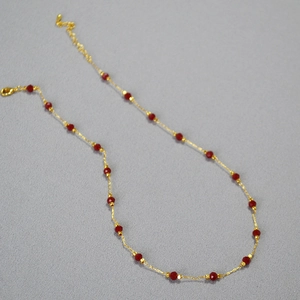 Detailed view of gold plated brass necklace with faceted red spinel beads and lobster clasp