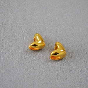 Boucles d'oreilles cœur plaquées or avec finition miroir polie sur tissu gris texturé