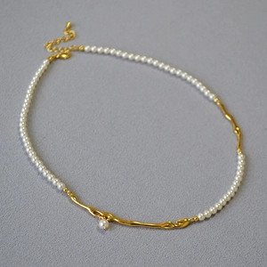 Détail d'un collier vintage français avec perles blanches et maillons dorés en branche