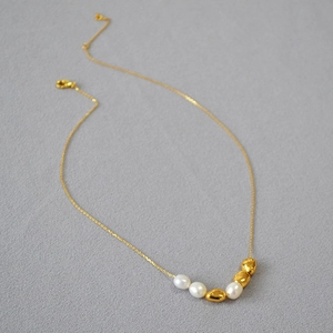 Baroque freshwater pearl and gold bead choker necklace on minimalist grey background