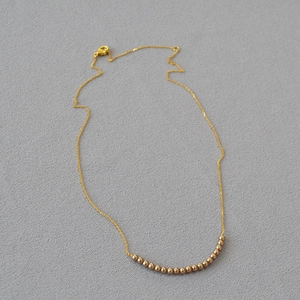 Detail of elegant gold chain necklace featuring round coffee-gold beads and lobster clasp
