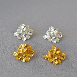 Detailed macro view of layered floral studs in gold and silver matte finishes