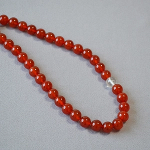 Macro shot of red agate beads with a transparent crystal center on a textured background