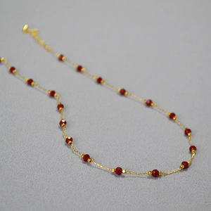 Detail of red faceted spinel beads on a gold-plated brass chain necklace for women