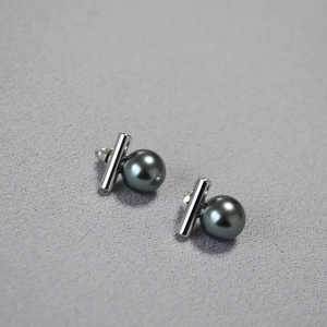 Gros plan sur des boucles d'oreilles perles noires avec barre en argent épurée