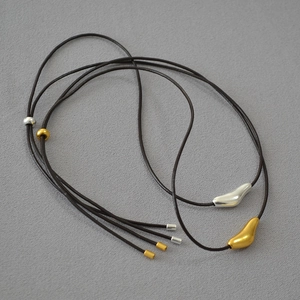 Close-up of adjustable leather cord necklace with abstract brass bird pendants and beads