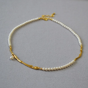 Détail du collier élégant pour femme avec branche plaquée or et perles blanches