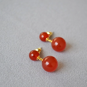 Macro shot of French design red agate earrings with double spheres and gold hardware