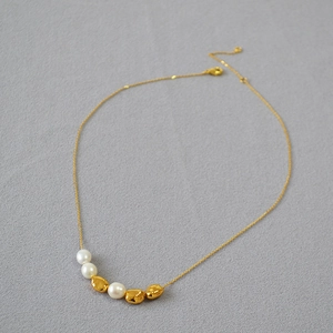 Detail view of irregular baroque pearls and gold beads on a minimalist collar necklace