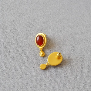 Detailed view of vintage gold earrings with oval red agate and teardrop pendants