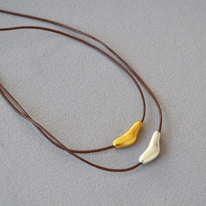 Detail of organic abstract bird pendant in polished gold and matte silver on cord