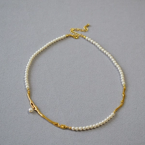 Détail du collier en laiton doré avec perles blanches et fermoir à texture de lave fusion