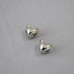 Boucles d'oreilles cœur en argent poli miroir présentées sur un fond en tissu gris