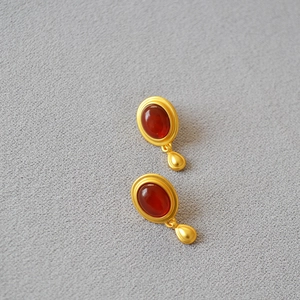 Macro detail of vintage teardrop earrings with red agate gemstone and matte gold finish