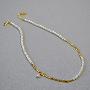 Vue détaillée du pendentif branche en laiton doré avec une perle pendante sur un collier