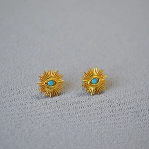 Detailed close-up of sunburst gold-plated stud earrings with turquoise evil eye stones